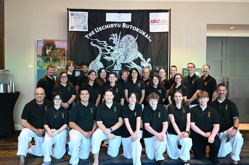 Facilitator’s Guild members wearing black shirts in front of a Uechiryu Butokukai banner