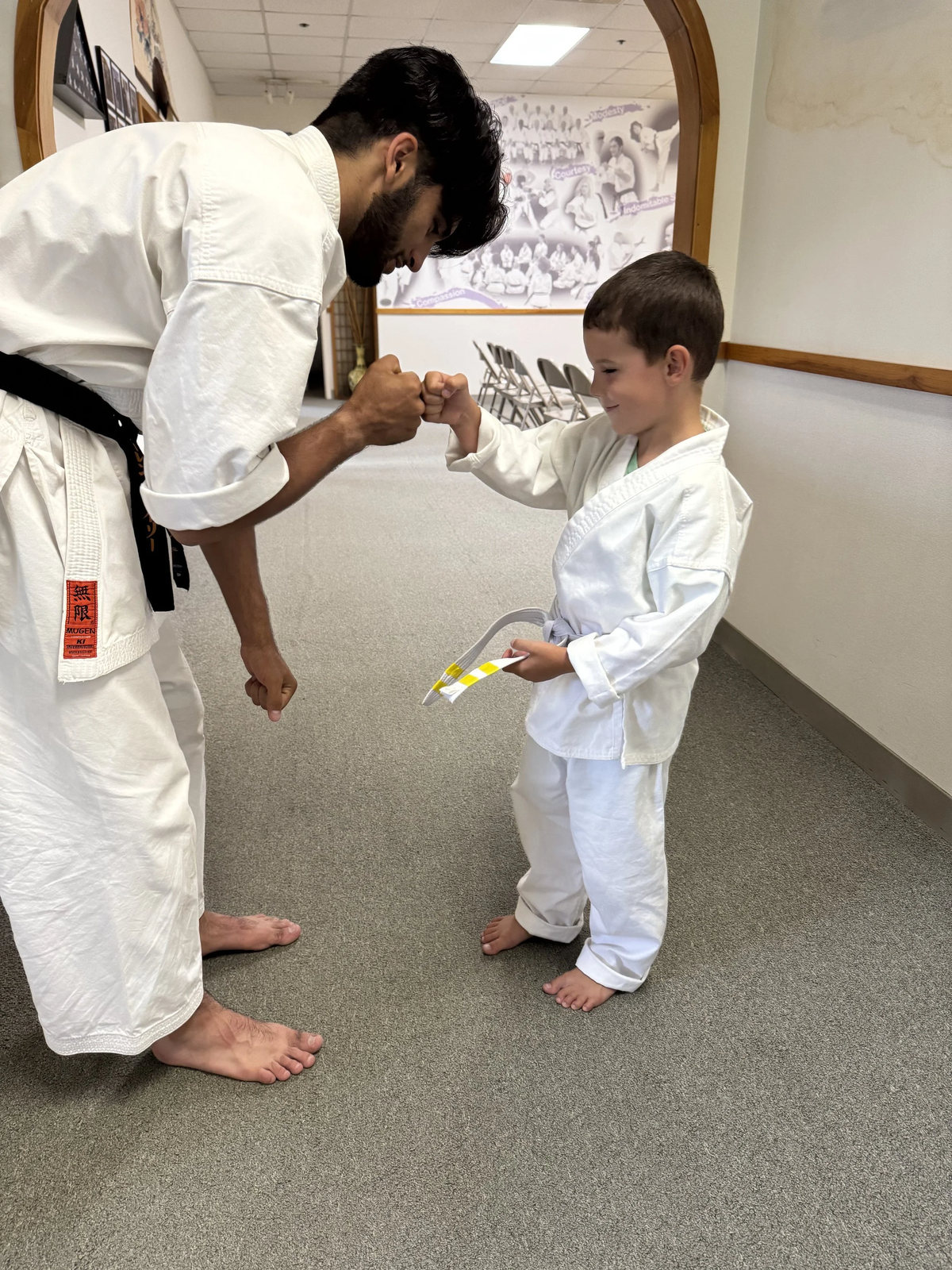 Henry Traynor exchanging a fist bump with a junior karate student