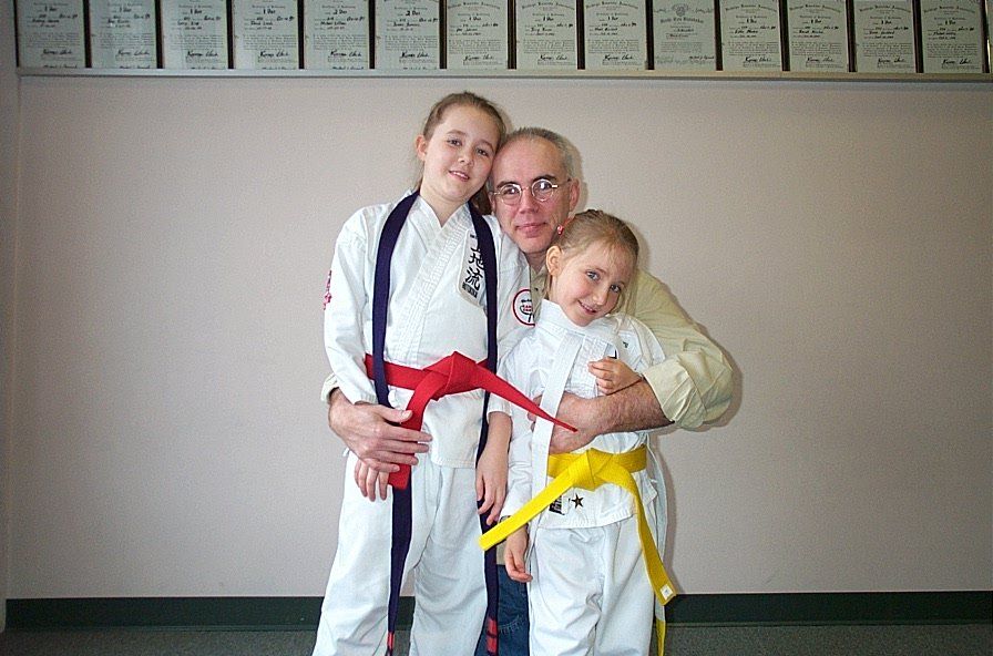 Jeff MacDonald in a karate uniform with two children