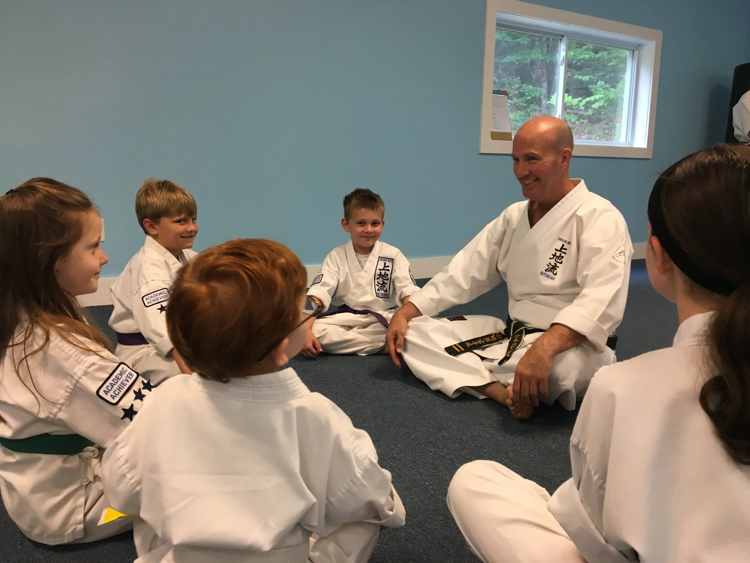 Neil Stone seated with junior karate students